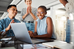 Group of diverse businesspeople having a meeting in an office at work. Happy business professionals clapping for their colleagues achievement together. Joyful african american businesswoman being applauded by her coworkers - WorldTone